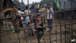 木栅栏里面是孟加拉国与缅甸交界处的古杜帕隆难民营，这名罗兴亚儿童9月5日刚刚从缅甸进入到孟加拉一侧。